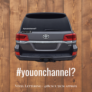 Back view of a Toyota Land Cruiser with vinyl lettering on a wooden background