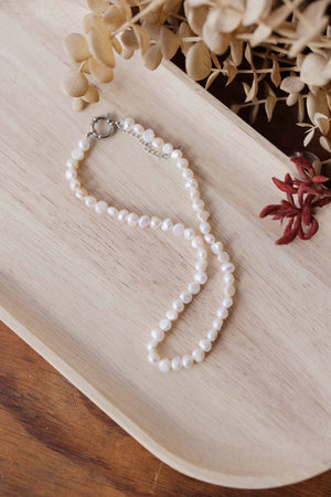 Pearl necklace on a wooden tray with decorative elements